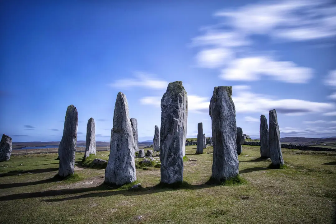 The tall grey stones of the second Callanish circle on Lewis under a blue sky