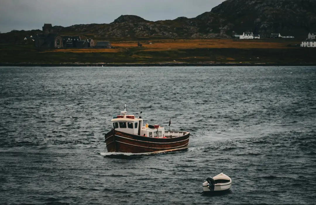 A small wooden boat crossing grey water off Mull
