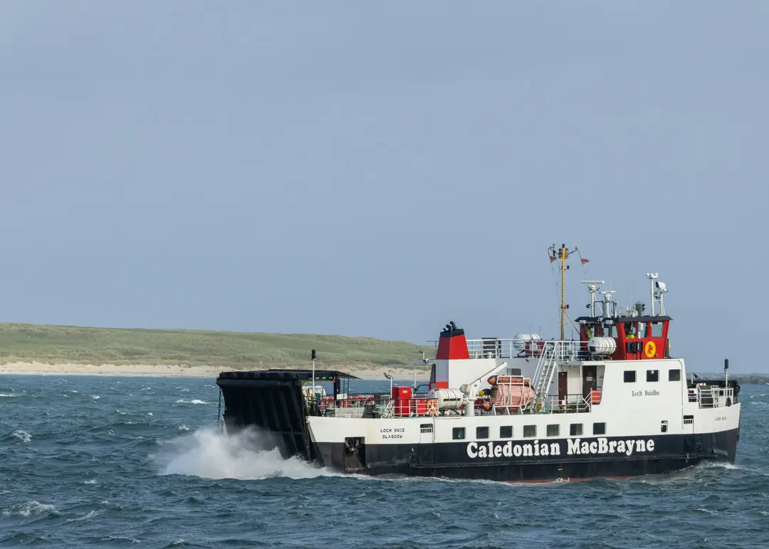 A small CalMac ferry crossing from Fionnphort past a white sand shore