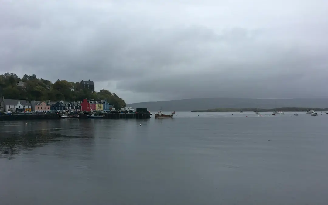 Tobermory's painted harbour front on Mull under grey cloud, the bay flat calm