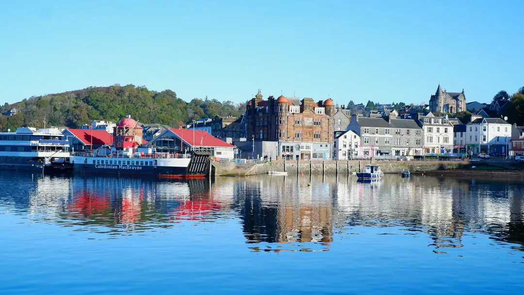 Oban harbour on a still morning, a ferry at the pier and the town reflected in the water