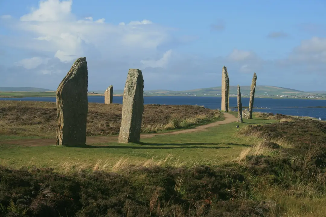 Two tall standing stones on Orkney farmland with water beyond