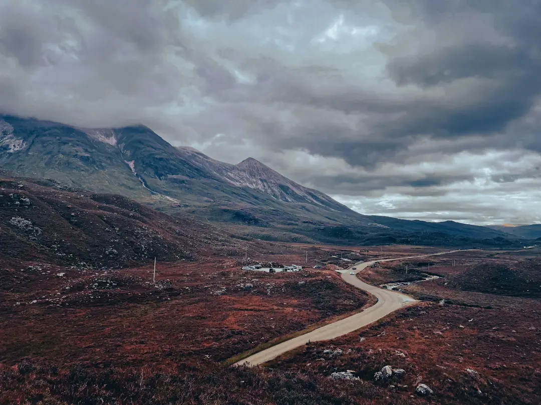 The road winding through Glen Torridon below rust-coloured hills and heavy cloud
